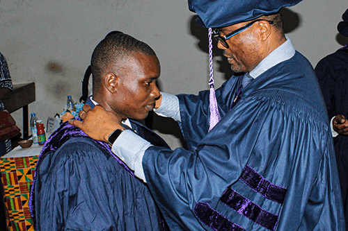 Dr. Binyang receiving his academic regalia from Prof. Wondji