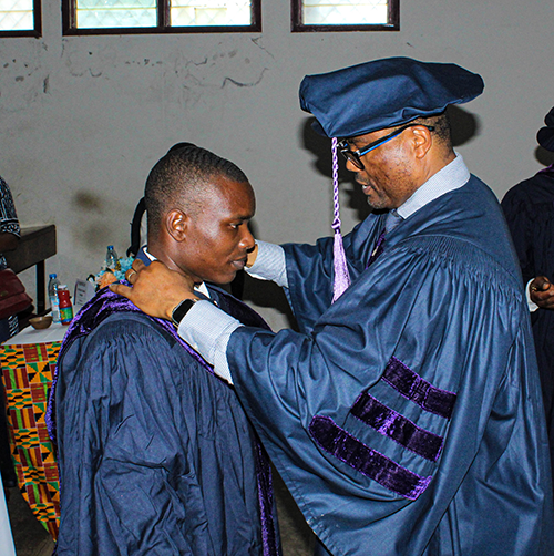 Dr. Binyang receiving his academic regalia from Prof. Wondji
